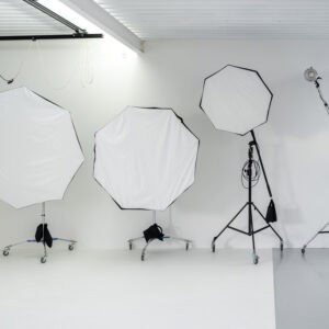 Éclairage studio avec parapluies et trépieds dans un espace lumineux.