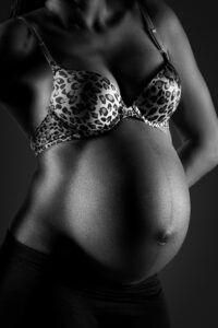 Gros plan sur le ventre d'une femme enceinte en lingerie léopard, en noir et blanc.