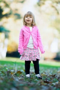 Enfant souriante en vêtements colorés dans un parc de Plainpalais, Genève, lors d'une séance photo p.